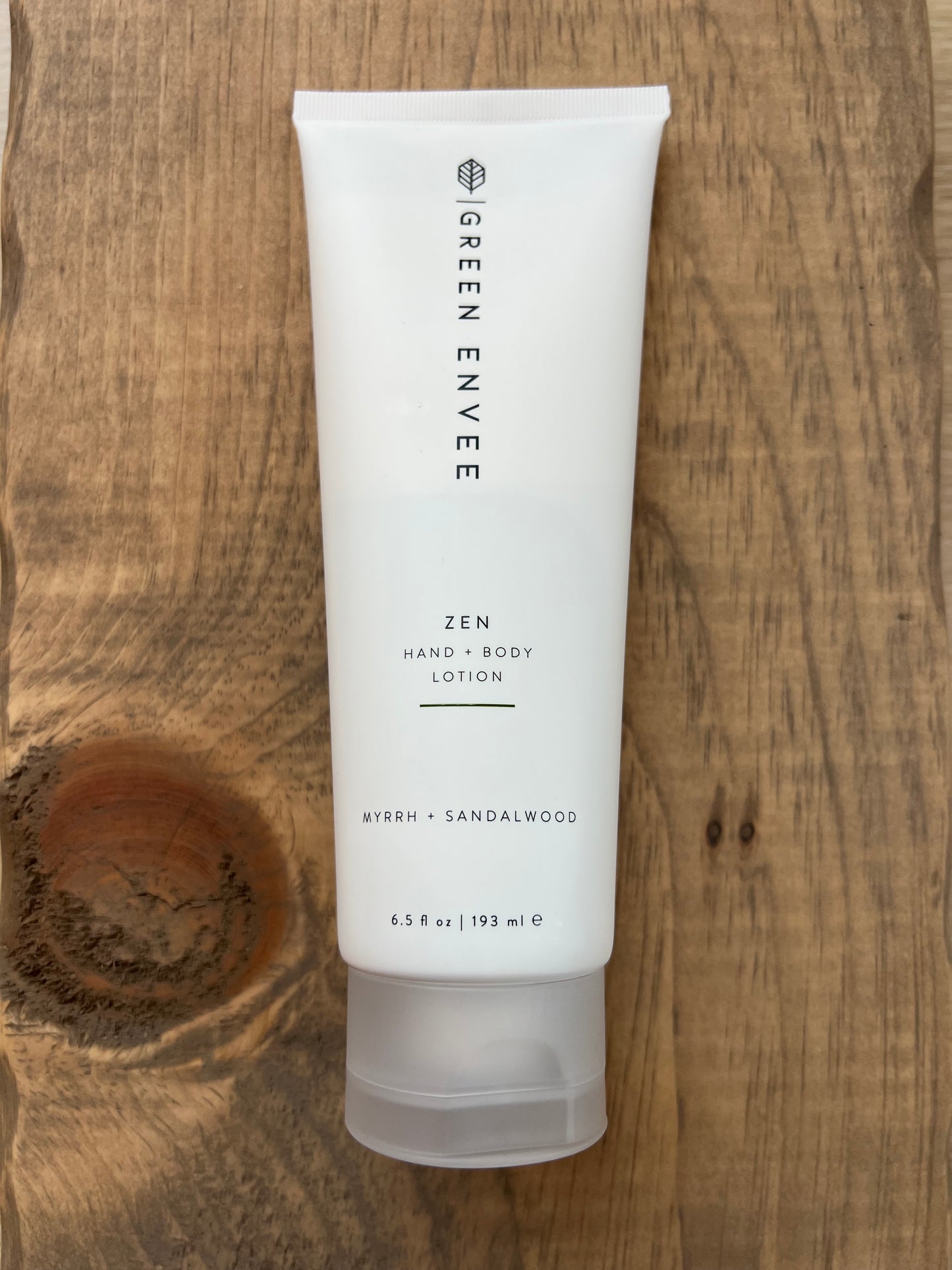 White lotion tube labeled 'Green Envee' on a wooden surface