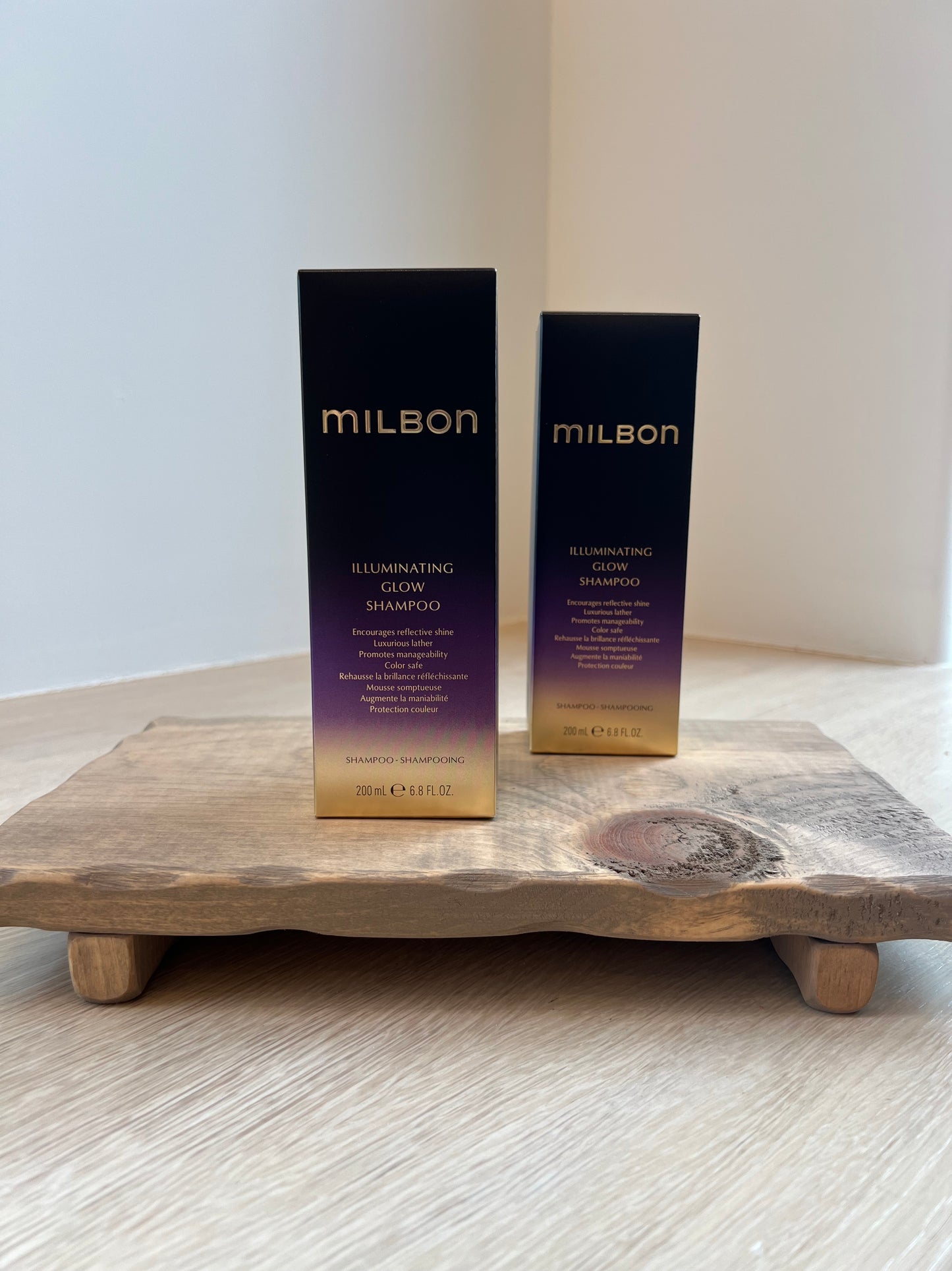 Two bottles of Milbon hair care product on a wooden tray against a white background