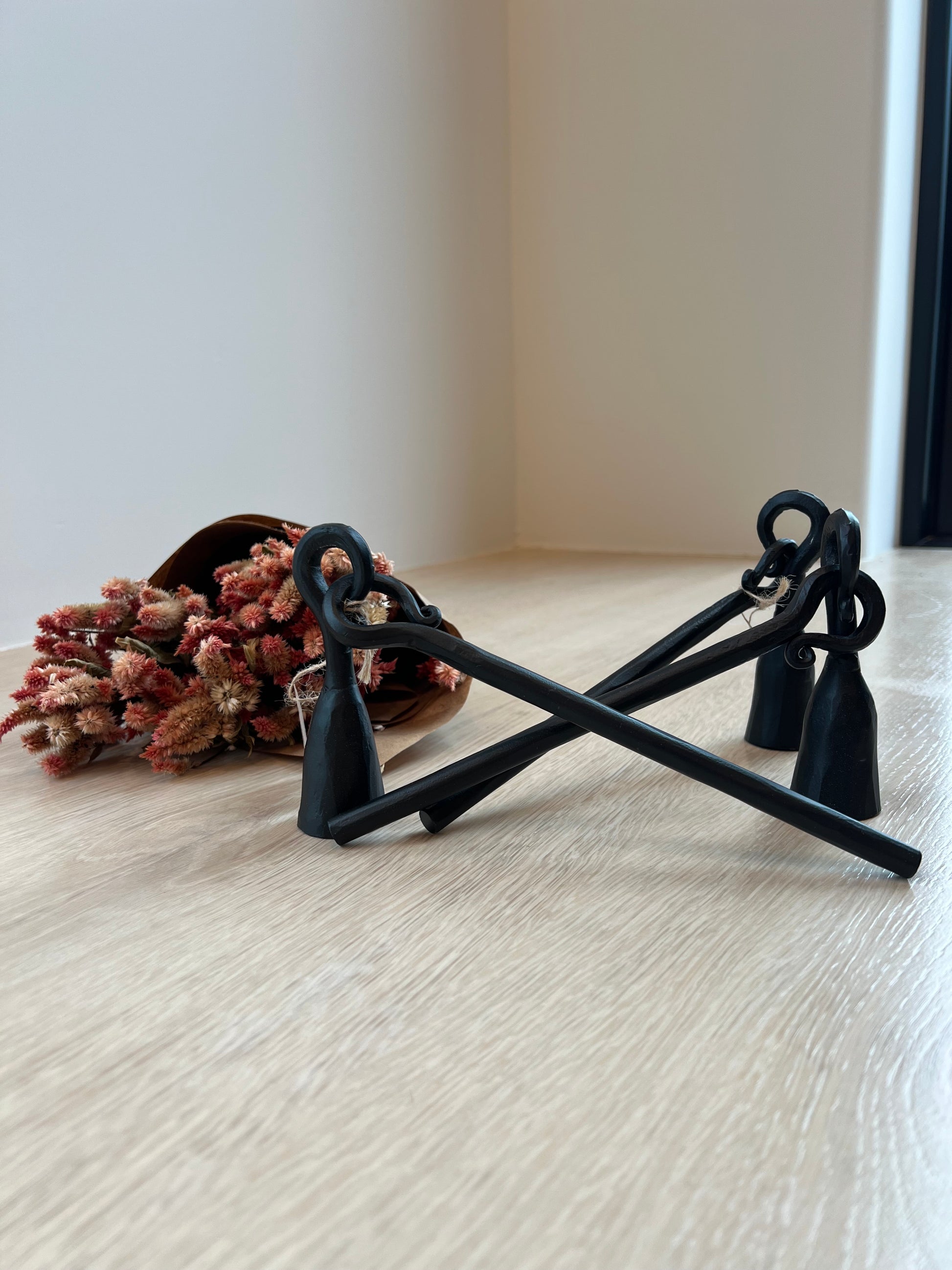 Decorative candle snuffer with dried flowers on a white wall