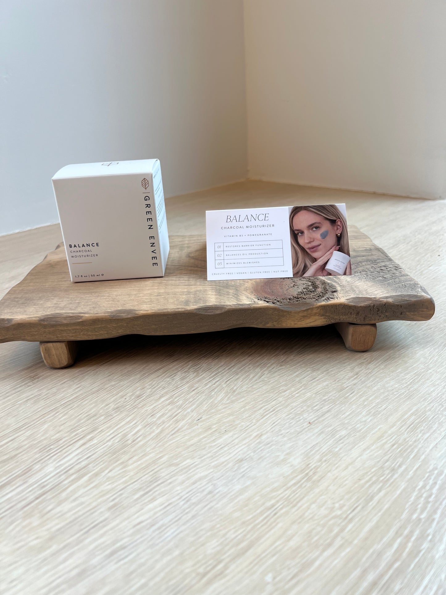 Wooden tray with a Balance Charcoal Moisturizer product box and card on a white surface