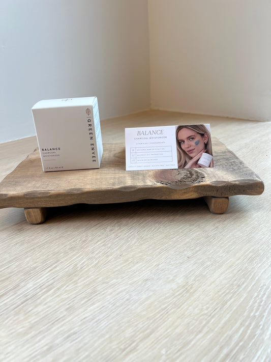 Wooden tray with a Balance Charcoal Moisturizer product box and card on a white surface