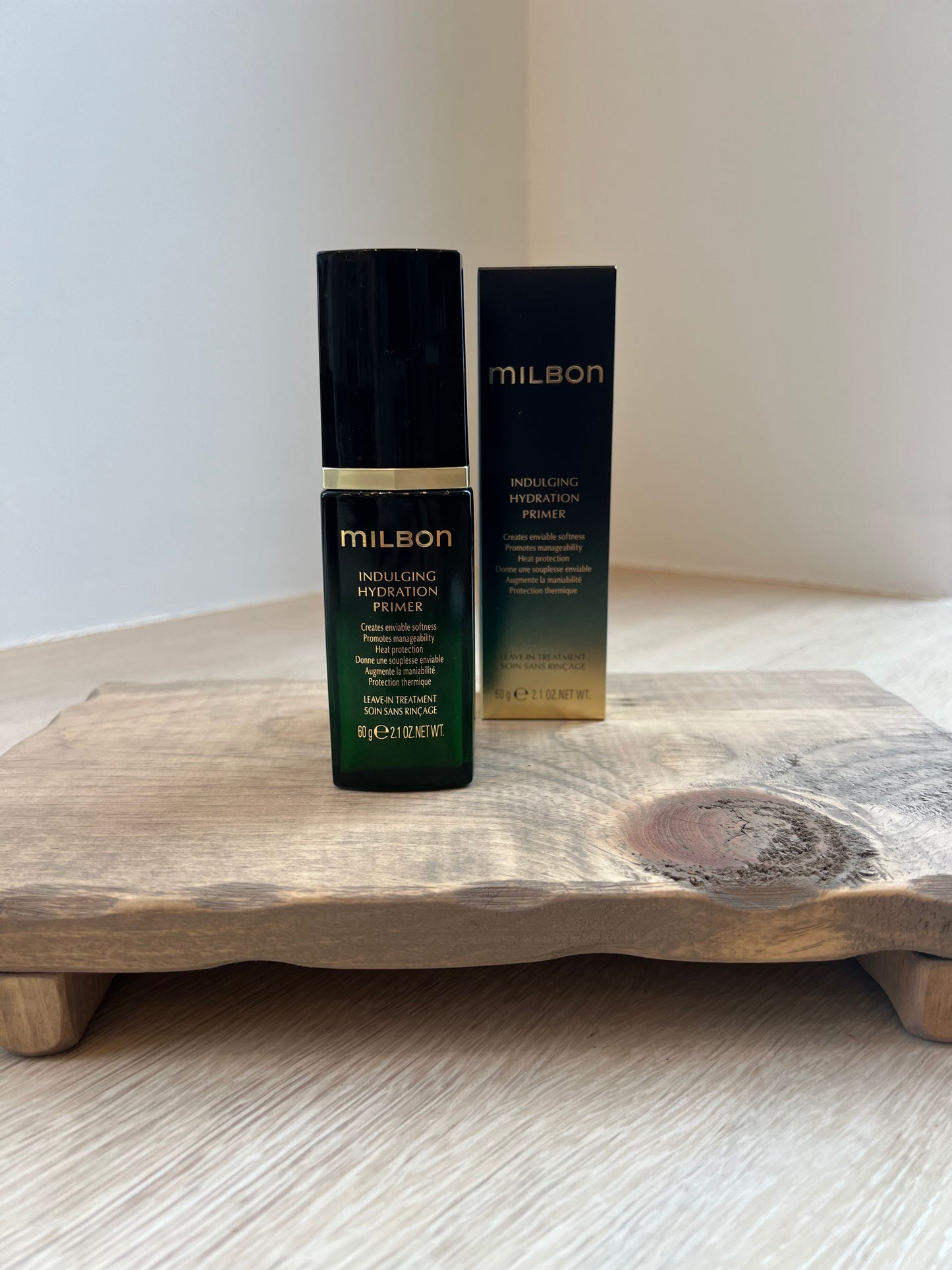 Two black cosmetic bottles with gold accents on a wooden surface